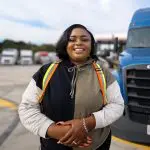 A woman standing in front of a truck.